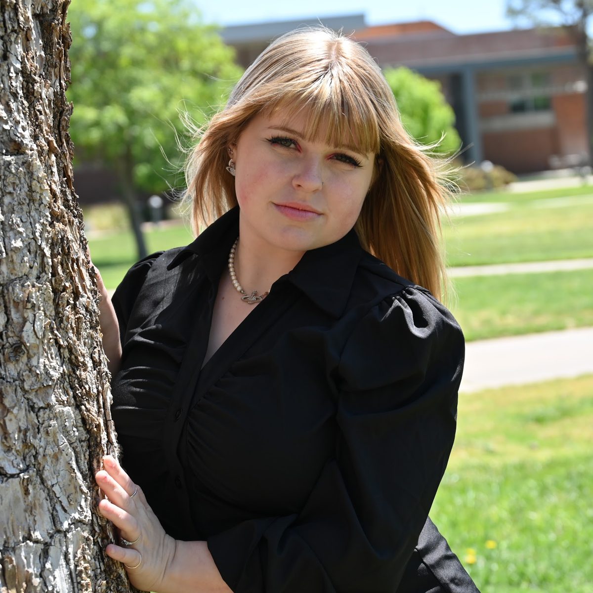 Haley Tarrant leaning against a tree on a sunny day