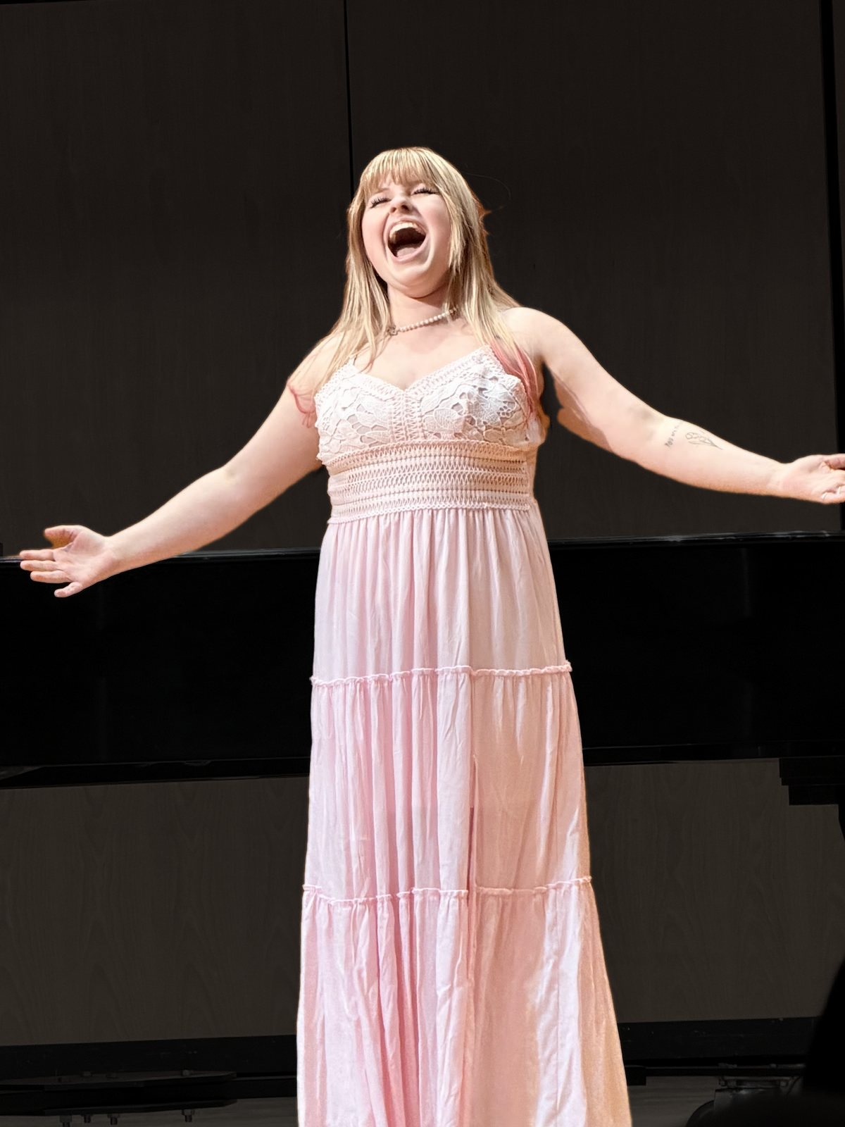 Haley Tarrant singing in recital in a blush gown